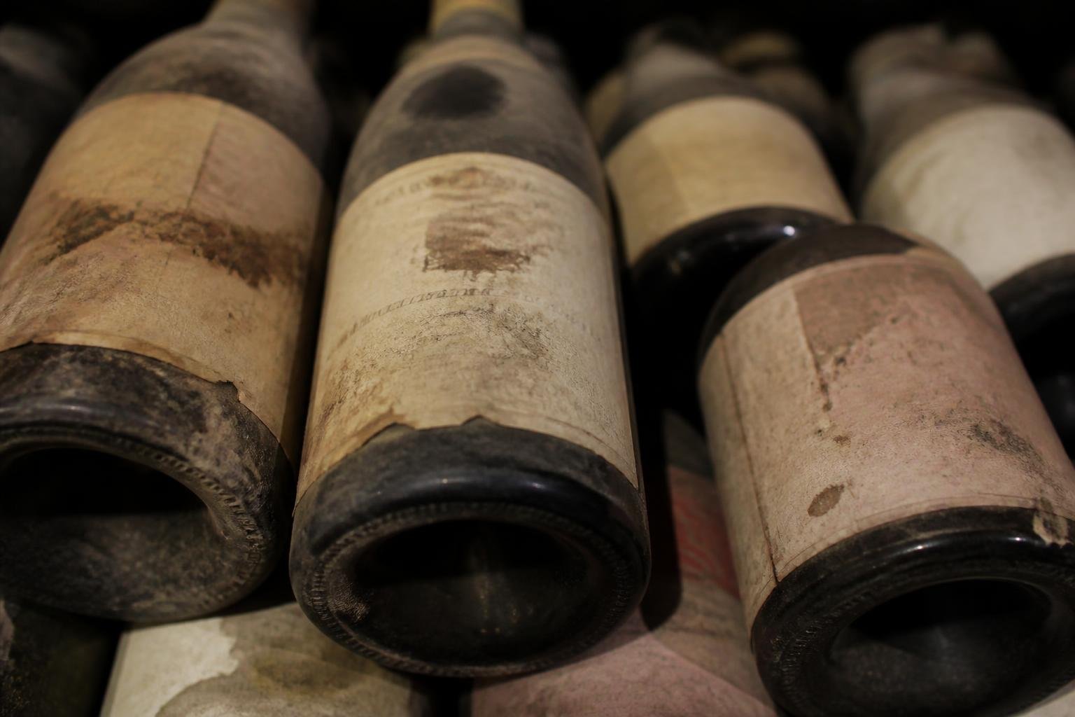 Détail de bouteilles de vin de Bourgogne empilées, étiquettes authentiques et historiques